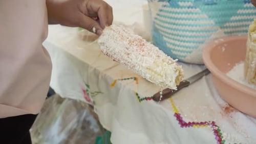 Close-up of person adding seasonings to traditional corn on the cob dish. Mexico.