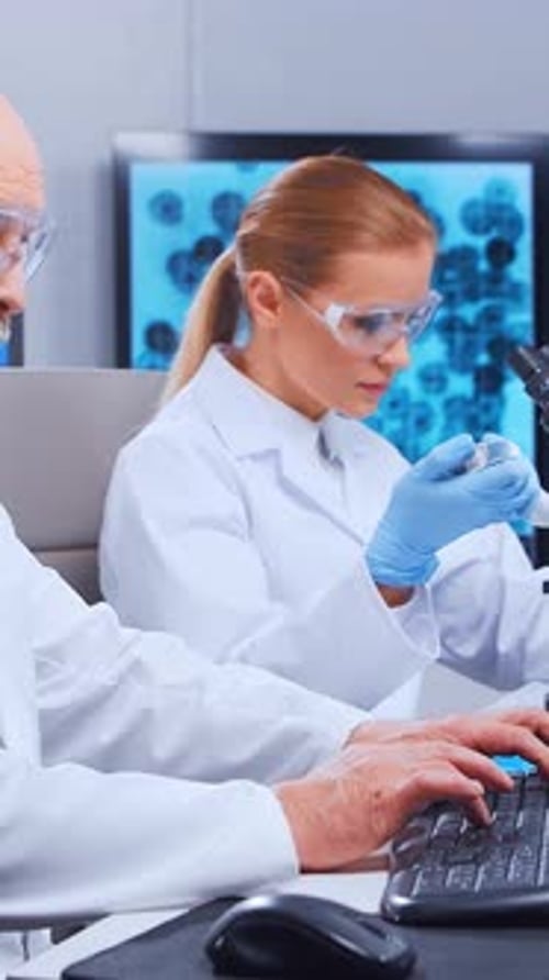 Scientists working in lab with microscope and computer