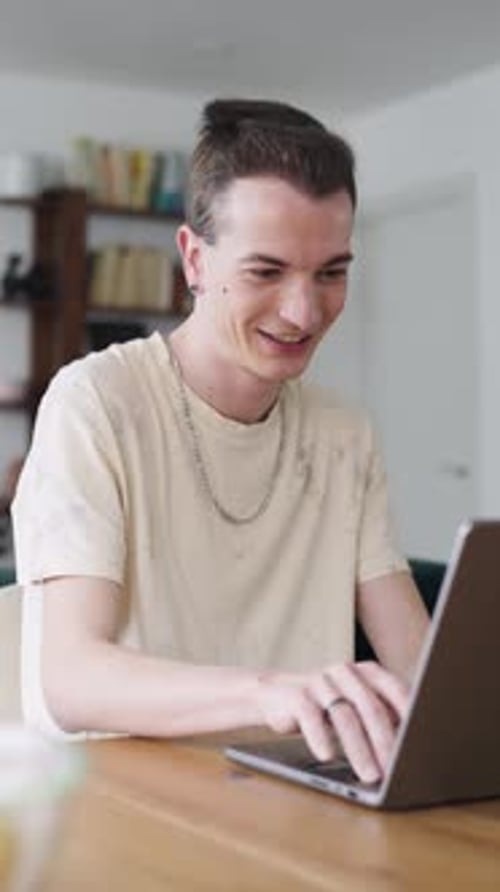 Young Man Using Laptop at Table Inside