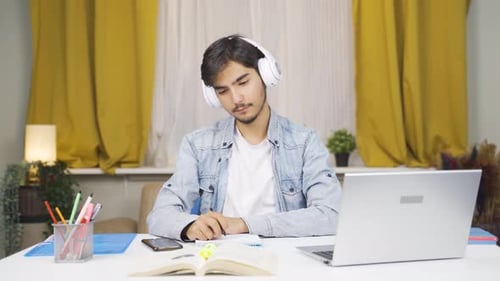 Man Writing in Notebook While Listening to Music