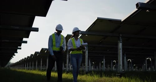 Asian Young Inspector Engineer man and female colleague checking operation in solar farm