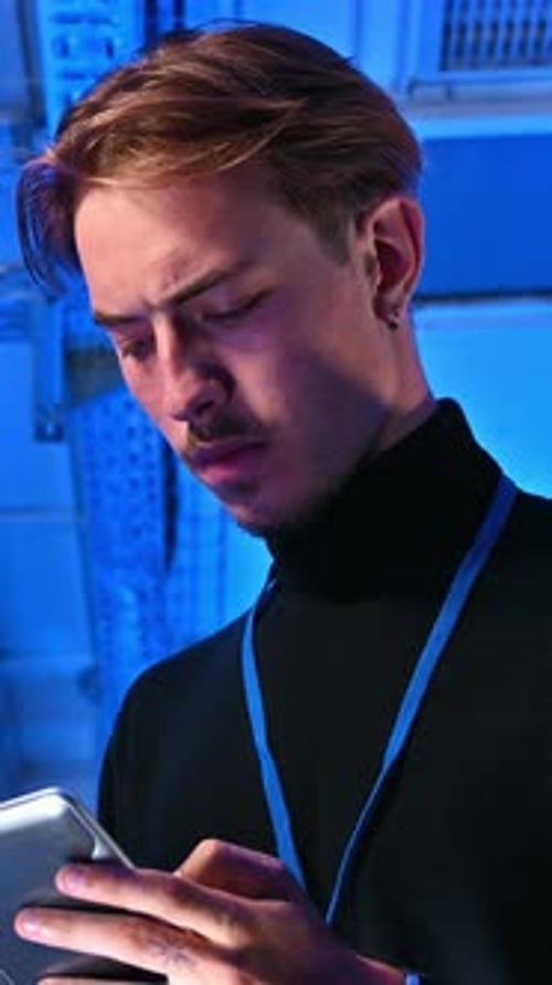 Man Uses Tablet in Blue-Lit Server Room