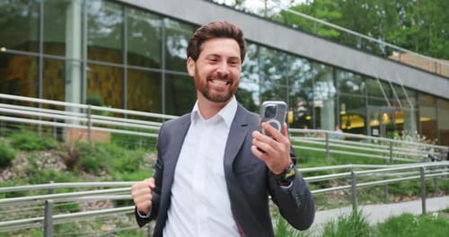 Successful Businessman Celebrates Holding Smartphone Outdoors