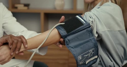 Black Doctor Measuring Blood Pressure to a Young Woman at Office