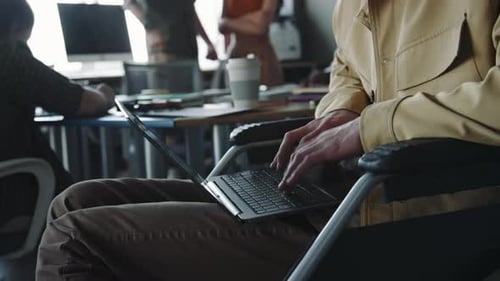 Young Man with Disability Typing on Laptop at Work in Office