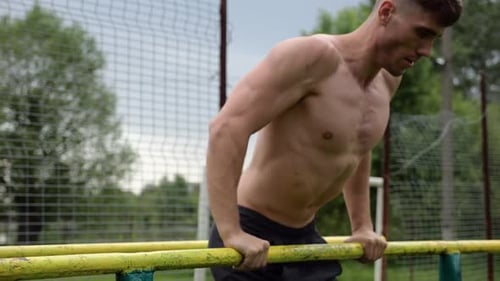 Muscular Man Doing Dips on Parallel Bars