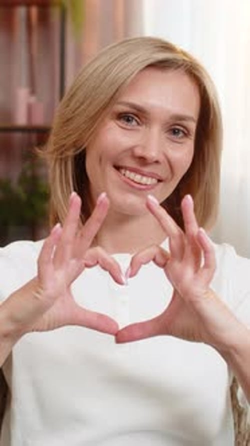 Smiling Woman Makes Heart Shape with Hands