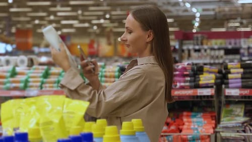 Woman Uses Smartphone While Shopping in Supermarket