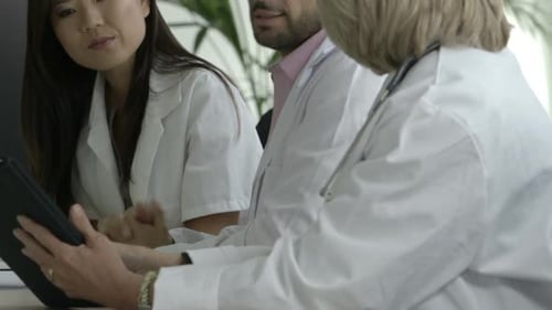 Medical professionals review information on tablet at workplace