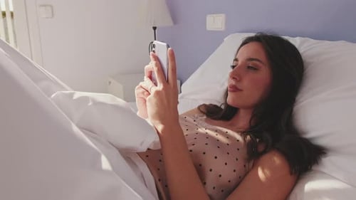 Young Woman Using Smartphone Lying in Bed