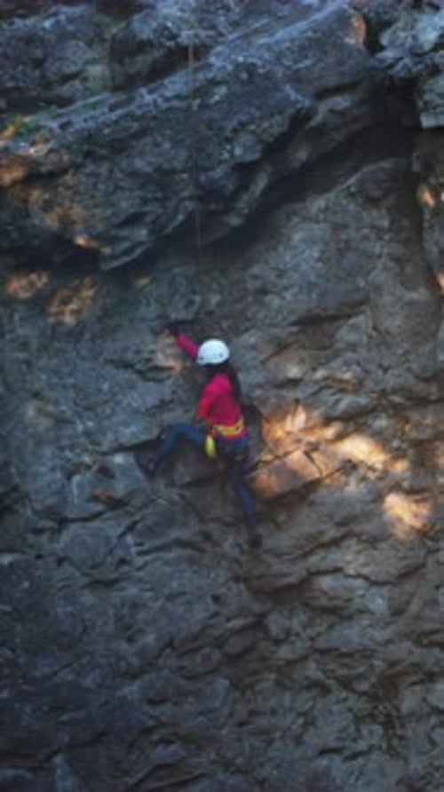 Female Climber Exploring Steep Cliffs Adventurous Female Climber in Natural Light Navigating Rocky