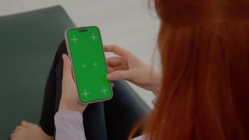 Woman in gym mat uses green screen smartphone during fitness break