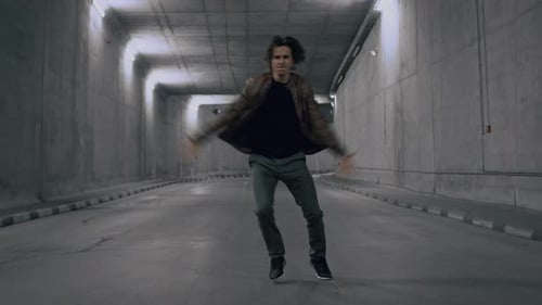 Serious Cool Young Hipster Man with Long Hair is Energetically Dancing Hip Hop in a Lit Concrete Tu