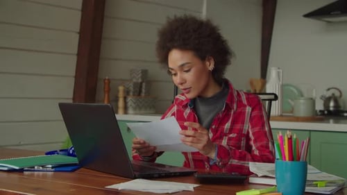 Woman Working on Laptop at Home with Bills