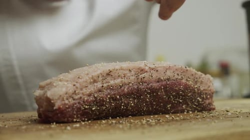 Adding spice onto meat steak on cutting board. Slow motion close up shot.
