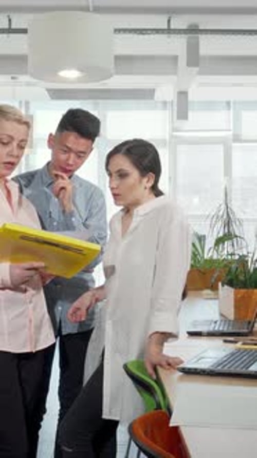 Dynamic Business Team Collaborating on Documents in a Modern Office