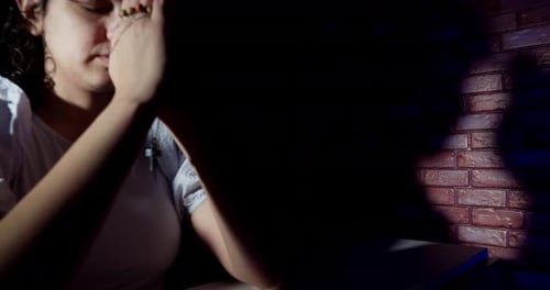 Teen Girl with Hand on Face in Dark Room