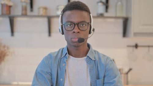 Young African Man with Headset Looking toward Camera in Call Center
