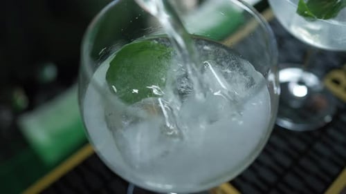 Pouring Drink into Glass with Ice and Leaf
