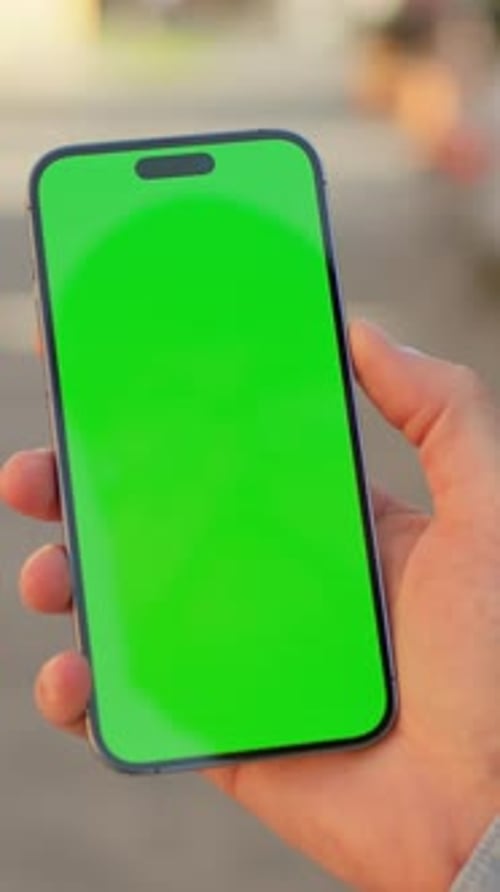 Closeup Shot of Male Caucasian Hand in Jeans Shirt Holding Black Smartphone with Green Screen