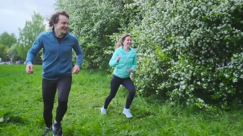 Sportive young people running. Couple run in the city park during the day