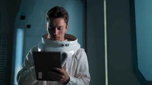 A Man in an Astronaut Costume with an Electronic Tablet