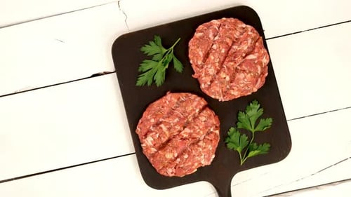Round Fresh Raw Mince Beef Burger Cutlet Ready to Prepare Rotate on Dark Kitchen Board