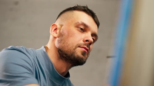 Closeup of a Young Artist in Blue Tshirt in an Art Studio Working on a Painting