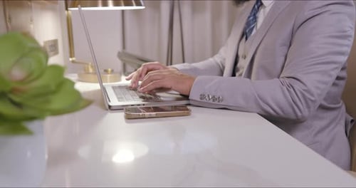 Man in Suit Typing on Laptop at Desk