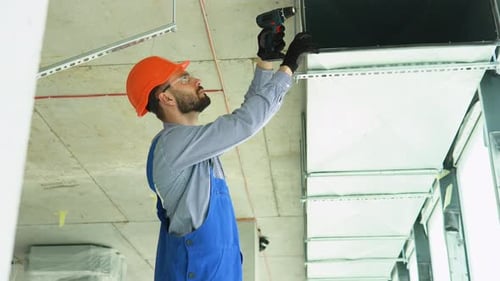 Construction Worker Installs Air Duct with Drill