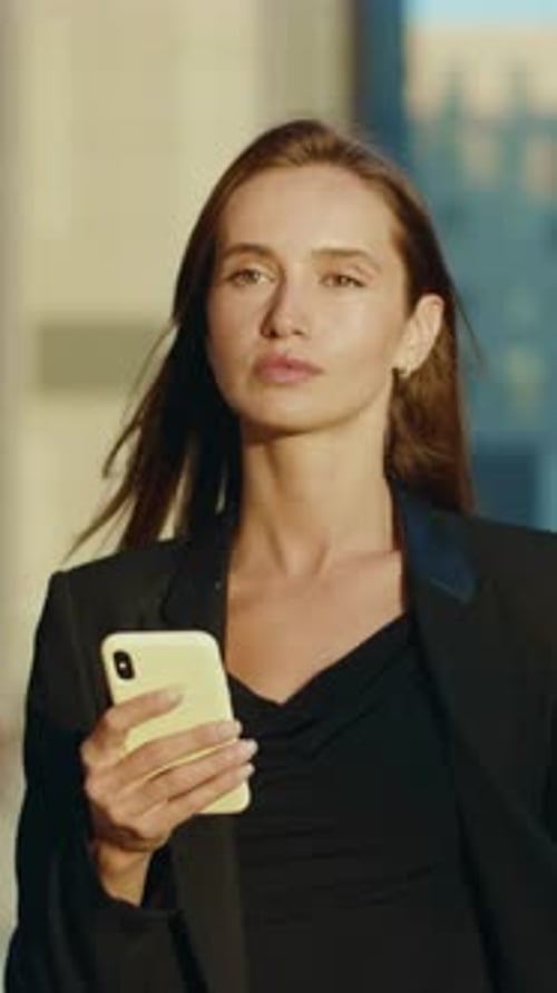 A Woman in a Black Jacket Uses Her Phone Showcasing Modern Communication