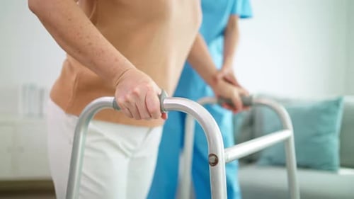 Senior Woman Using Walker with Nurse's Assistance