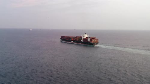 Aerial footage of a container ship approaching a commercial port.