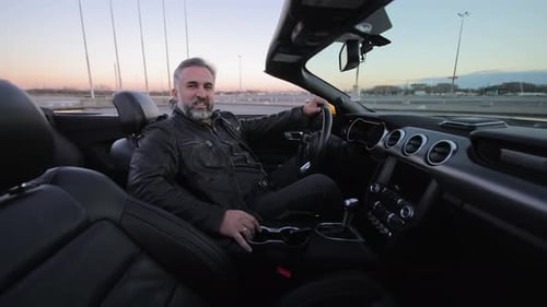 A Man Sits in a Luxurious Convertible Mature Man with a Content Expression Driving a Convertible Car