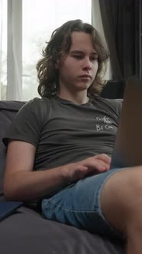 Young Adult Using Laptop on Couch Indoors