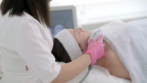 Relaxed Woman Receiving Facial Treatment at Clinic