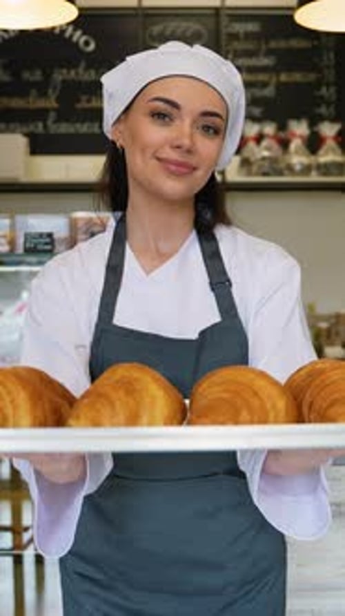 Woman Baker Holds Tray of Golden Croissants