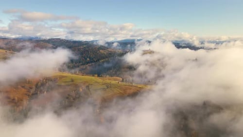 Aerial View of Mountain Hills Covered with Spruce Forest and White Dense Clouds Above at Bright