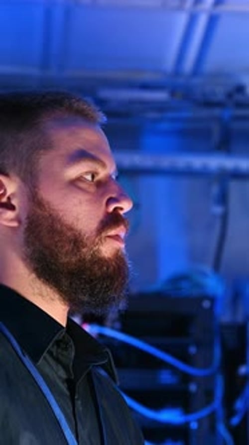 Focused Man Working in a Dark Server Room