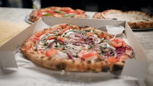 Delicious beautiful pizza with fish in a pizza box in a restaurant, ready for delivery