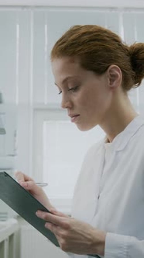Female Lab Worker Writes on Clipboard