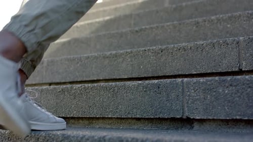 Male pushing sneaker against riser, shifting upward, planting on concrete steps toward landing