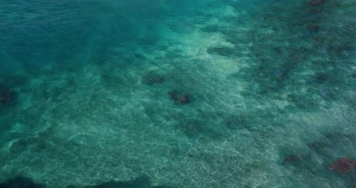 Colorful waters of the ocean, swirl around the rocky and scenic coastline. Sea waves breaking over r