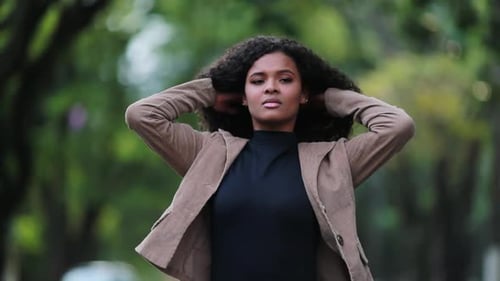 Woman Adjusts Jacket, Looks Around Outdoors