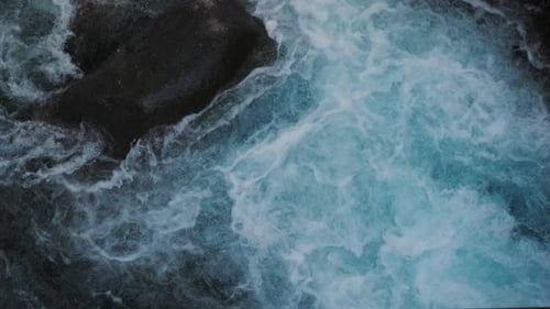 Plan filmé au ralenti de l'eau d'une rivière coulant sur des rochers. Texture détaillée de l'eau en mouvement avec du naturel