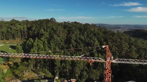 Guindaste aéreo - laranja que se estende acima de uma densa floresta com céu azul claro ao fundo