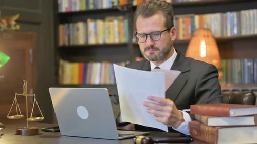 Middle Aged Lawyer Doing Paperwork on Laptop in Office