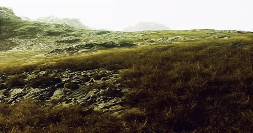 Vast Landscape Showcasing Rocky Terrain and Lush Grass Under a Misty Sky