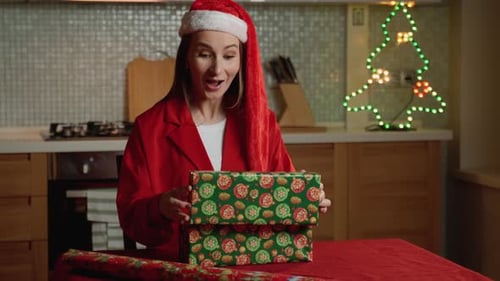 Woman Opening Christmas Gift in Kitchen