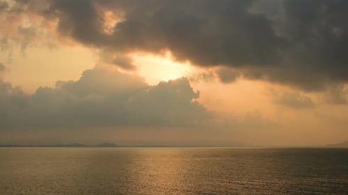 Timelapse d'un lever de soleil spectaculaire avec un ciel orange par temps nuageux au bord de l'océan.